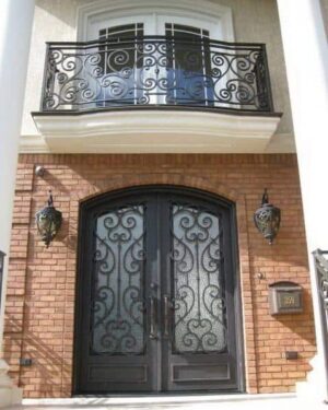 Arched wrought iron door EL1116 MCD with decorative grille and beveled glass, hand-forged for elegance and strength.