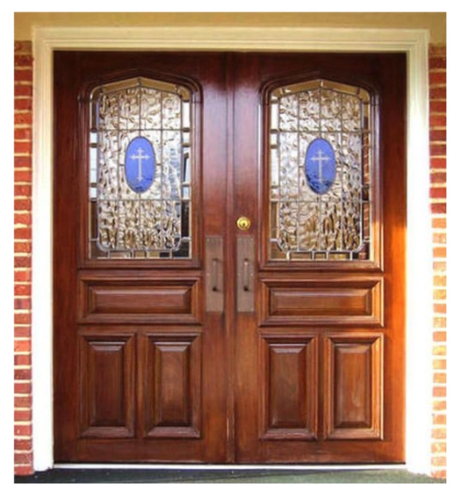 Double wood church entry doors with arched stained glass panels and cross medallions